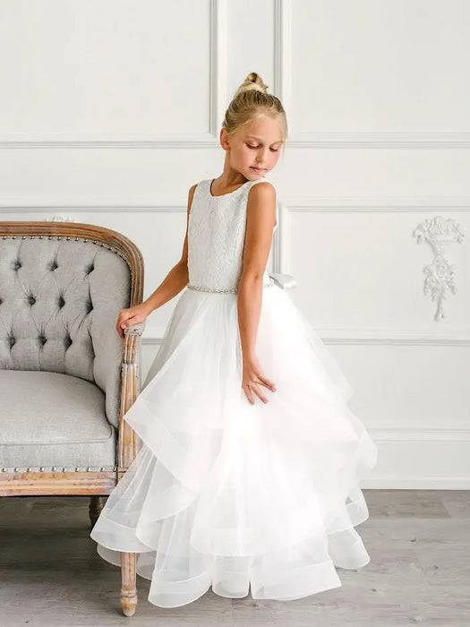 Teter Warm Cora Off White Communion Dress worn by a young girl standing beside a tufted chair.