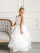 Teter Warm Cora Off White Communion Dress worn by a young girl standing beside a tufted chair.