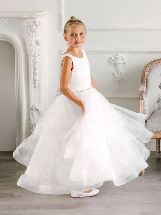 Teter Warm Cora off-white communion dress worn by a young girl standing in an elegant room.