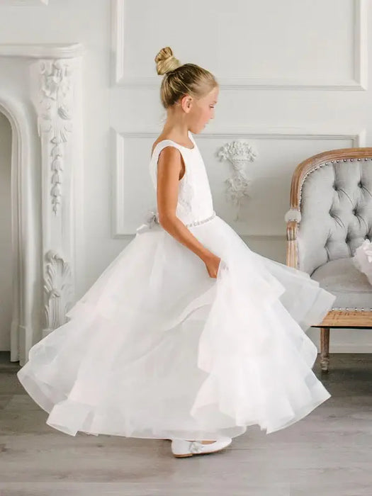 Teter Warm Cora off white communion dress on a young girl twirling in an elegant room.
