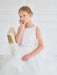 Teter Warm Cora Off White Communion Dress shown on a young girl sitting on a chair in a bright room.