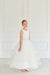 Teter Warm Cora off-white communion dress worn by a young girl standing in a bright room.