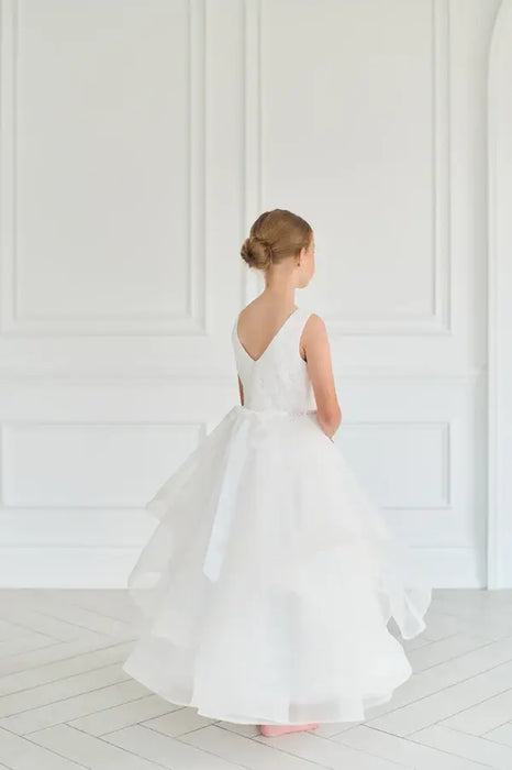 Teter Warm Cora off-white communion dress shown on a young girl standing in a bright room.