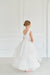 Teter Warm Cora off-white communion dress shown on a young girl standing in a bright room.