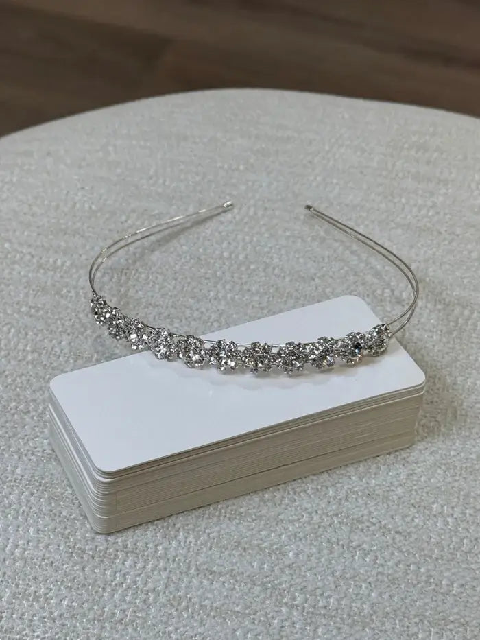 Teter Warm Crystalline Silver Flower Headpiece displayed on a stack of white cards on a textured surface.