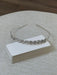 Teter Warm Crystalline Silver Flower Headpiece displayed on a stack of white cards on a textured surface.