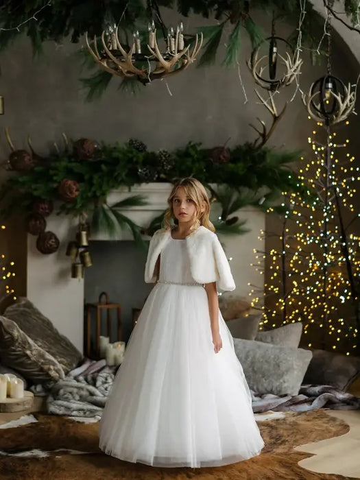 Teter Warm Dakota faux fur jacket worn by a girl over a white dress, standing in a cozy, festive living room.