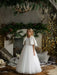 Teter Warm Dakota faux fur jacket worn by a girl over a white dress, standing in a cozy, festive living room.