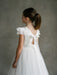 Emma Lace Communion Dress shown on a young girl with lace sleeves and a large back bow, viewed from behind.