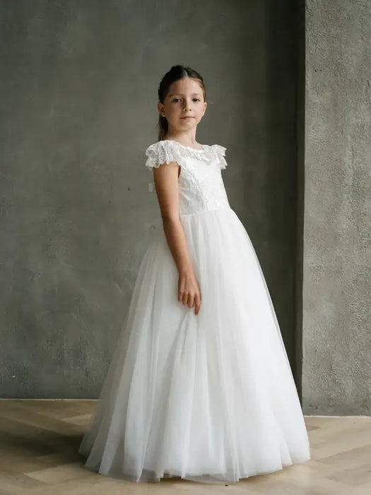 Teter Warm Emma Lace Communion Dress shown worn by a young girl standing indoors on a wood floor.