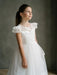 Emma Lace Communion Dress shown on a young girl standing indoors against a neutral background.