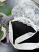 Teter Warm floral lace baby bonnet with satin ties displayed on a dark tabletop.