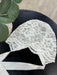 Teter Warm floral lace baby bonnet with satin ties displayed on a dark table.