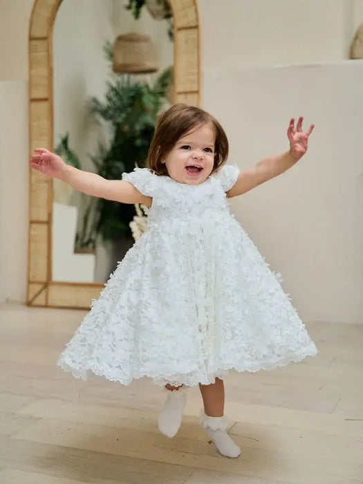Teter Warm Floral Off-White Lace Baptism Dress shown on a smiling toddler indoors