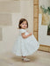 Teter Warm floral off-white lace baptism dress worn by a toddler standing indoors by a mirror.