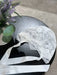Teter Warm floral soft lace bonnet with satin ribbons displayed on a black table beside a vase of flowers.