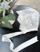 Teter Warm Floral Soft Lace Bonnet displayed on a black table next to a flower arrangement.