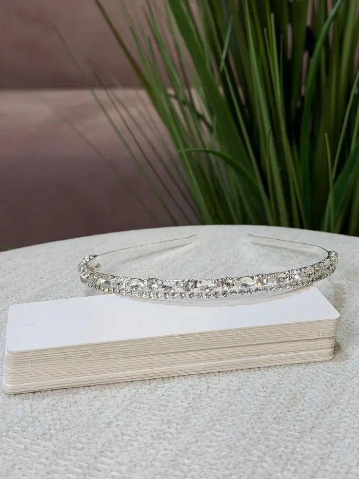 Teter Warm Gem Double Band Headpiece with sparkling crystals displayed on a table near green plants.