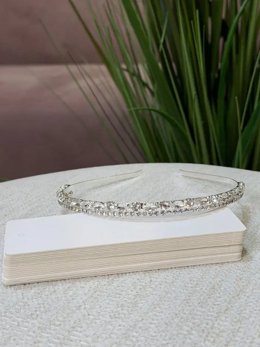 Teter Warm Gem Double Band Headpiece with sparkling crystals displayed on a table near green plants.