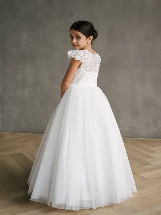 Teter Warm Gisele lace cap sleeve communion dress worn by a girl standing on a wooden floor