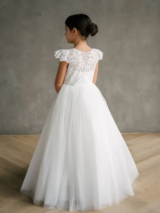 Gisele Lace Cap Sleeve Communion Dress shown on a girl standing with her back to the camera indoors.