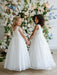 Teter Warm Hailey Lace Sequin Communion Dress shown on two girls holding hands in front of floral backdrop.