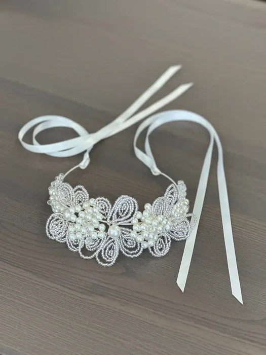 Teter Warm Hannah Pearl Headband with floral bead design and satin ribbons on a wooden surface.