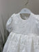 Teter Warm Hariet floral baptism dress with lace detail displayed on a hanger against a neutral background.