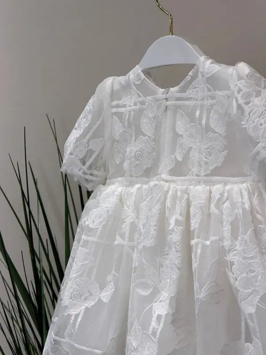 Teter Warm Hariet floral baptism dress with sheer lace and short sleeves shown on hanger.