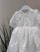 Teter Warm Hariet floral baptism dress with sheer lace and short sleeves shown on hanger.