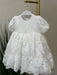 Teter Warm Hariet floral baptism dress with three-quarter sleeves, displayed on a hanger indoors.