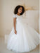 Heidi Sequin Bodice Communion Dress shown on a young girl standing in a neutral indoor setting.