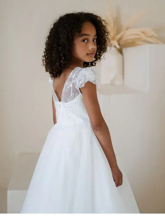 Heidi Sequin Bodice Comunion Dress worn by a girl, showing lace back and tulle skirt in a minimal room.