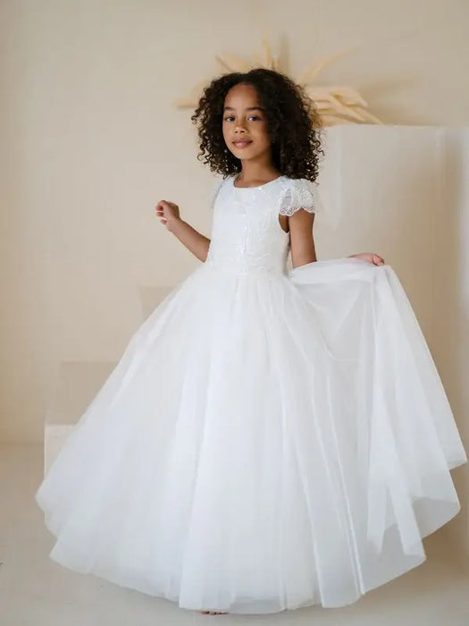 Heidi Sequin Bodice Communion Dress shown worn by a young girl posing indoors against a neutral background.