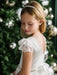 Teter Warm Julia Off White Lace Communion Dress worn by a girl standing near a decorated Christmas tree.