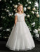 Teter Warm Julia off white lace communion dress worn by a girl standing in front of a decorated Christmas tree.