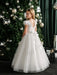 Teter Warm Julia off-white lace communion dress worn by a girl standing beside a decorated Christmas tree.