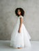 Teter Warm Lenni off-white communion dress worn by a girl standing sideways against a neutral background.