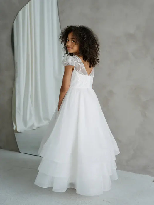 Teter Warm Lenni off-white communion dress with lace sleeves shown on a girl standing indoors.