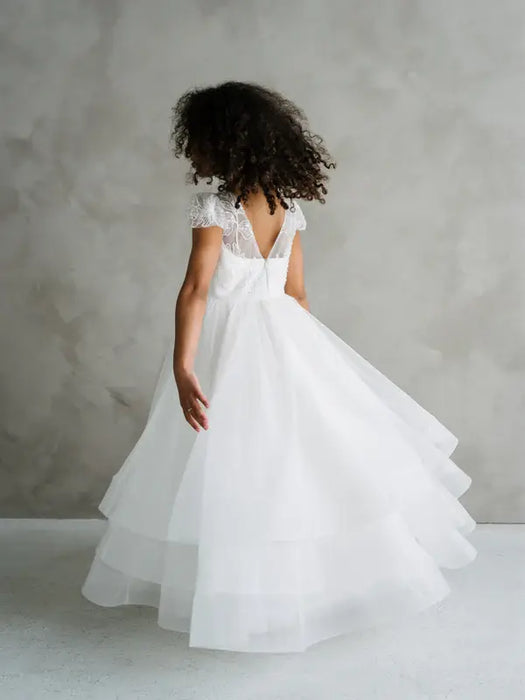 Teter Warm Lenni off-white communion dress with lace sleeves, shown on a girl turning indoors.