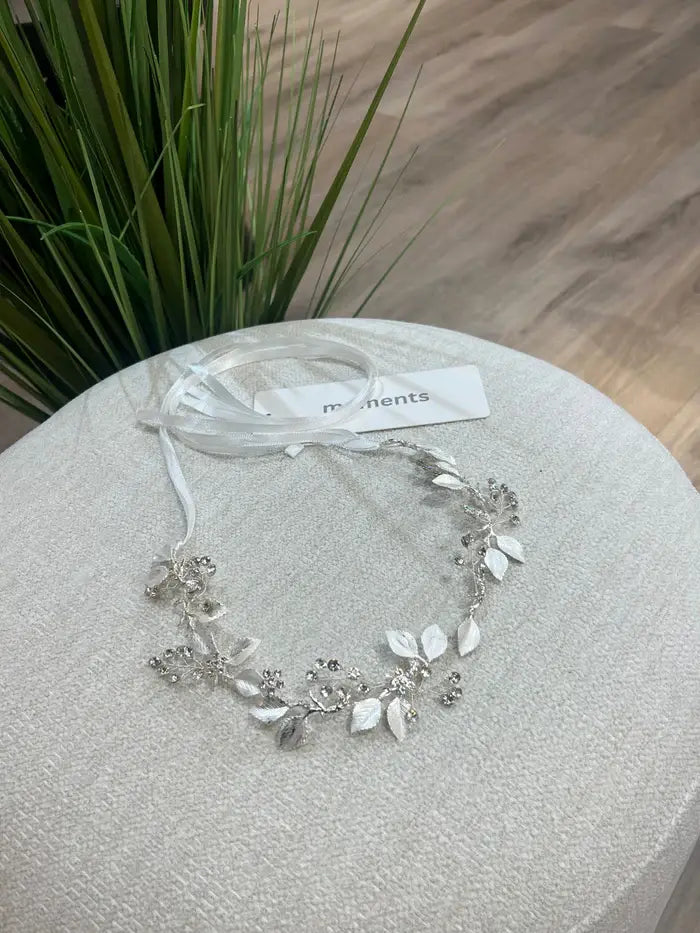 Teter Warm Leslie silver rhinestone headpiece with leaf and floral design displayed on a light fabric surface.