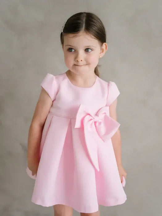 Teter Warm Lettie pink party dress with large bow, worn by a young girl against a neutral background.
