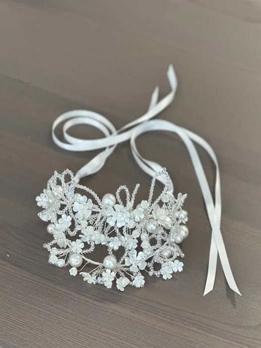 Lillian Pearl Double Band Headpiece with floral and pearl details, displayed on a wood surface.