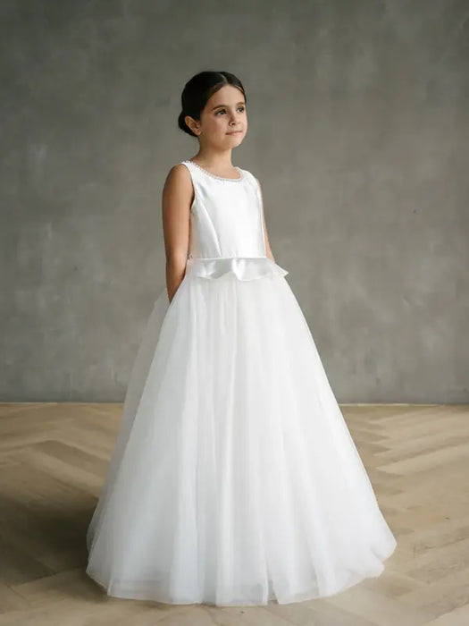 Liza Satin Communion Dress shown on a young girl standing indoors against a neutral background.