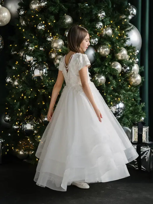 Teter Warm Marietta communion dress worn by a girl standing in front of a decorated Christmas tree.