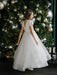 Teter Warm Marietta communion dress worn by a girl standing in front of a decorated Christmas tree.
