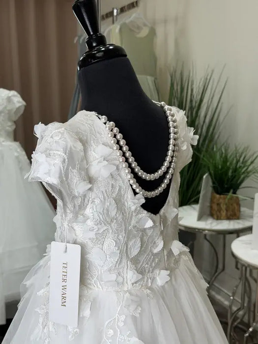 Teter Warm Marietta communion dress with floral lace and pearls displayed on a mannequin indoors.