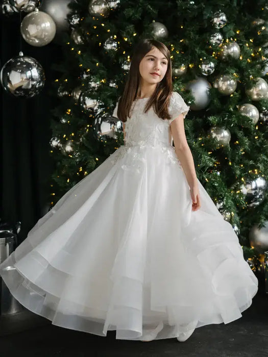 Teter Warm Marietta communion dress shown on a young girl standing in front of a decorated tree.