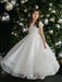 Teter Warm Marietta communion dress shown on a young girl standing in front of a decorated tree.