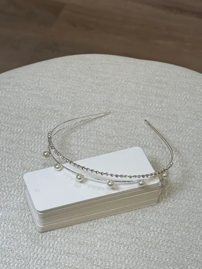 Teter Warm Mika pearl rhinestone double headband displayed on a stack of white cards on a beige surface.